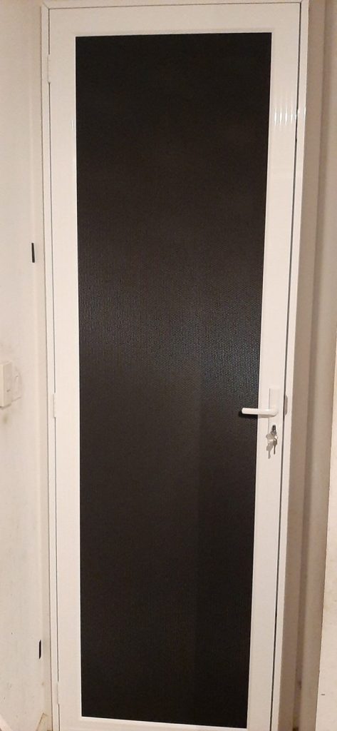 A white door with black glass in a room, showcasing Security Screen Doors Adelaide by Knight Shutters and Improvements.