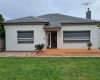Grey aluminium roller shutters fitted to windows of a cream brick Adelaide home