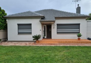 Grey aluminium roller shutters fitted to windows of a cream brick Adelaide home