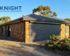 Charcoal roller shutters closed over a west-facing window on a brick home in Adelaide