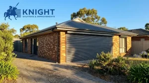 Charcoal roller shutters closed over a west-facing window on a brick home in Adelaide