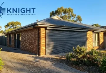 Charcoal roller shutters closed over a west-facing window on a brick home in Adelaide