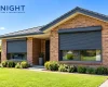 Dark grey roller shutters half lowered on a brick home in Adelaide on a sunny summer morning